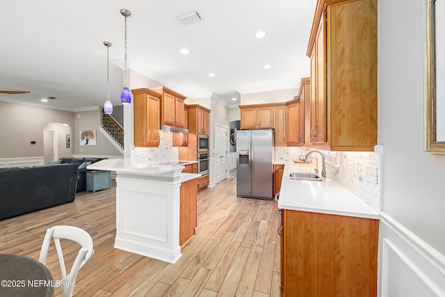 kitchen featuring open floor plan, stainless steel appliances, light countertops, and a sink