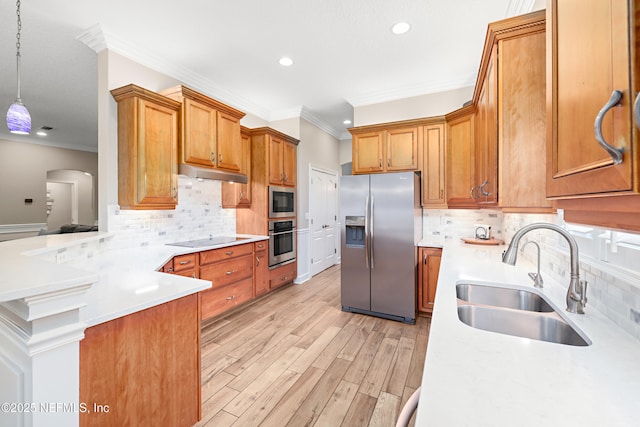 kitchen with under cabinet range hood, light countertops, brown cabinets, stainless steel appliances, and a sink