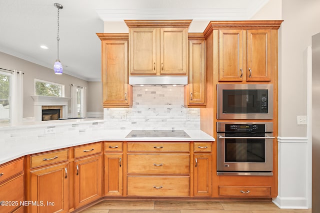 kitchen featuring under cabinet range hood, backsplash, stainless steel oven, built in microwave, and black electric stovetop