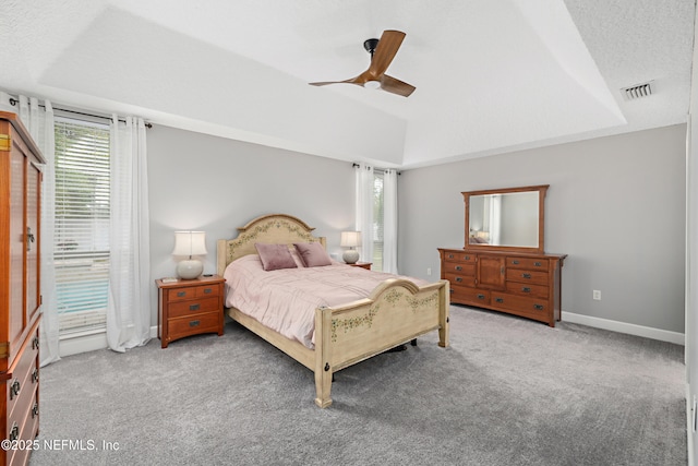 carpeted bedroom featuring visible vents, baseboards, a textured ceiling, a raised ceiling, and a ceiling fan