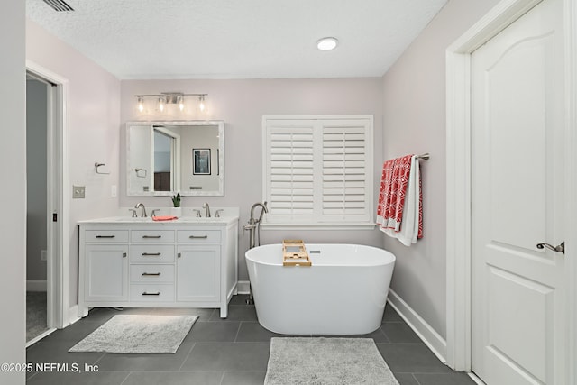 full bath featuring a sink, tile patterned flooring, double vanity, baseboards, and a soaking tub