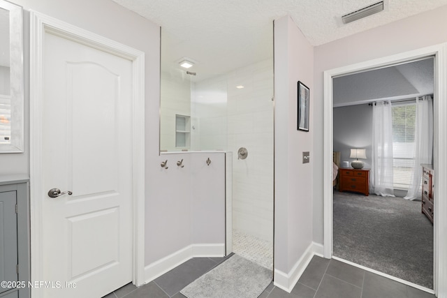 bathroom with tile patterned floors, visible vents, a walk in shower, a textured ceiling, and connected bathroom