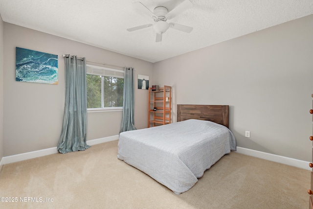 carpeted bedroom with a textured ceiling, baseboards, and a ceiling fan