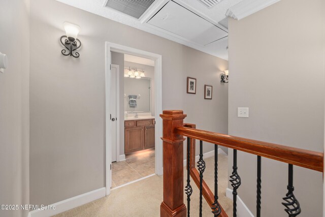 hall with visible vents, baseboards, attic access, an upstairs landing, and light carpet