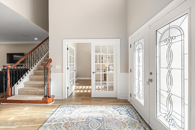 entrance foyer featuring french doors, a healthy amount of sunlight, wood finished floors, and stairs