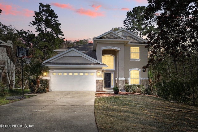 view of front of home featuring an attached garage, brick siding, concrete driveway, a yard, and stucco siding