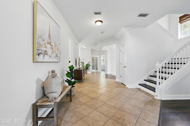 entrance foyer featuring tile patterned floors, visible vents, baseboards, and stairs