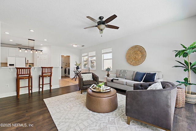 living room featuring recessed lighting, dark wood-type flooring, washing machine and dryer, a ceiling fan, and baseboards