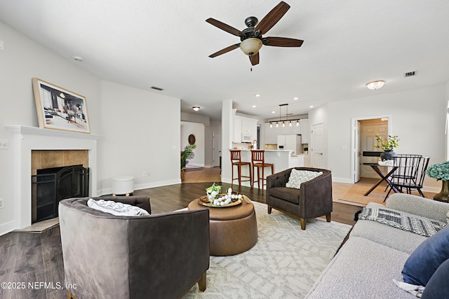 living area featuring a fireplace, recessed lighting, visible vents, wood finished floors, and baseboards