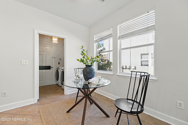 dining space featuring light tile patterned floors, baseboards, and washer and clothes dryer