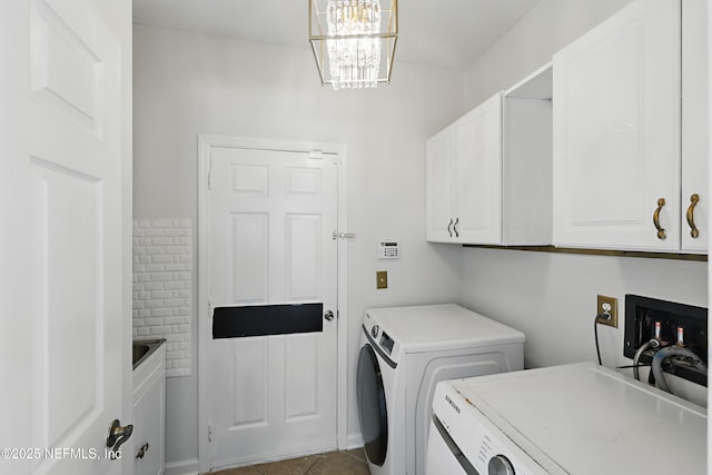 washroom featuring cabinet space, washer and clothes dryer, a notable chandelier, and tile patterned floors