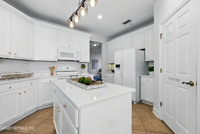 kitchen with light countertops, visible vents, white cabinets, a kitchen island, and white appliances