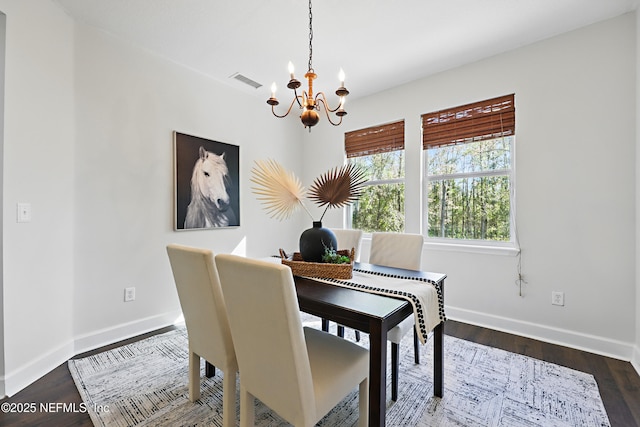 dining space with dark wood-style floors, baseboards, visible vents, and a chandelier