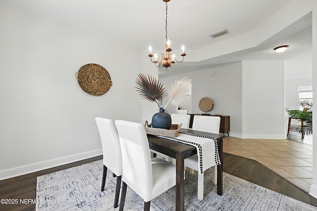 dining room with a chandelier, wood finished floors, visible vents, and baseboards