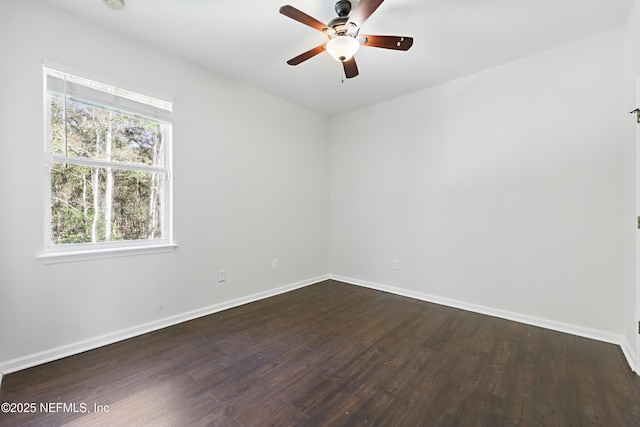 spare room with dark wood-type flooring, ceiling fan, and baseboards