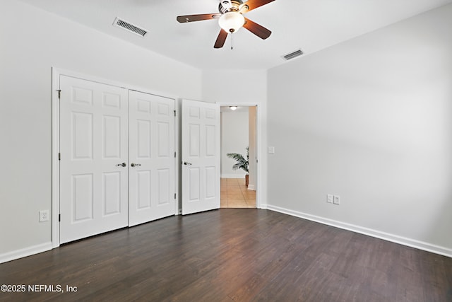 unfurnished bedroom with baseboards, a closet, visible vents, and wood finished floors