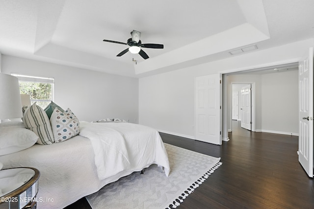 bedroom featuring a raised ceiling, visible vents, baseboards, and dark wood-style flooring