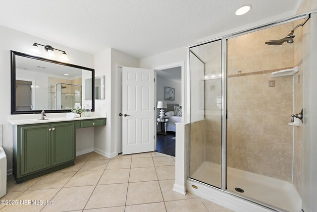 bathroom with a textured ceiling, vanity, baseboards, a shower stall, and tile patterned floors