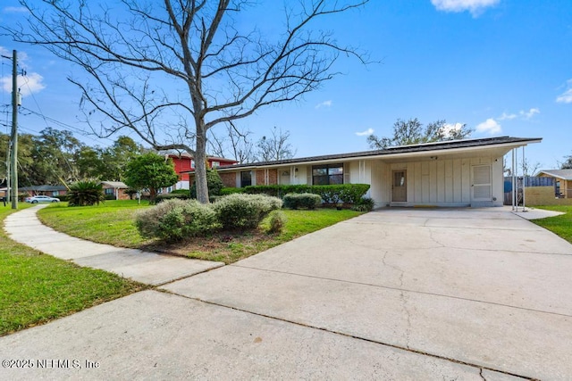 view of front of home with board and batten siding, an attached carport, concrete driveway, and a front lawn