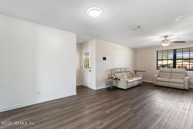 unfurnished living room featuring a textured ceiling, dark wood-style flooring, a ceiling fan, and baseboards