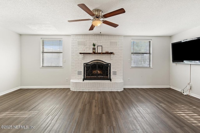 unfurnished living room featuring a textured ceiling, a brick fireplace, dark wood finished floors, and baseboards