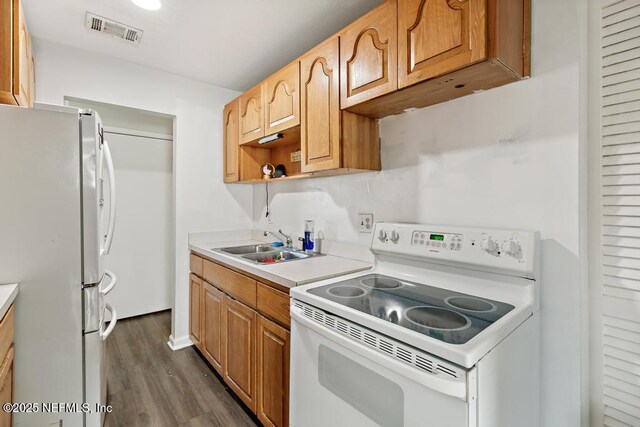 kitchen featuring white appliances, dark wood-style flooring, a sink, visible vents, and light countertops