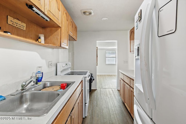 kitchen featuring dark wood-style flooring, light countertops, visible vents, a sink, and white appliances