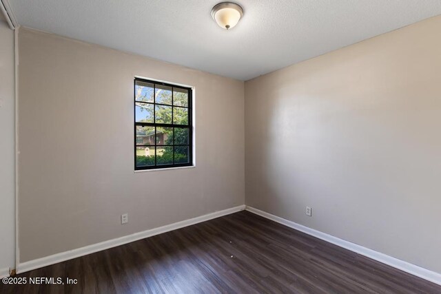 unfurnished room featuring dark wood-style floors and baseboards