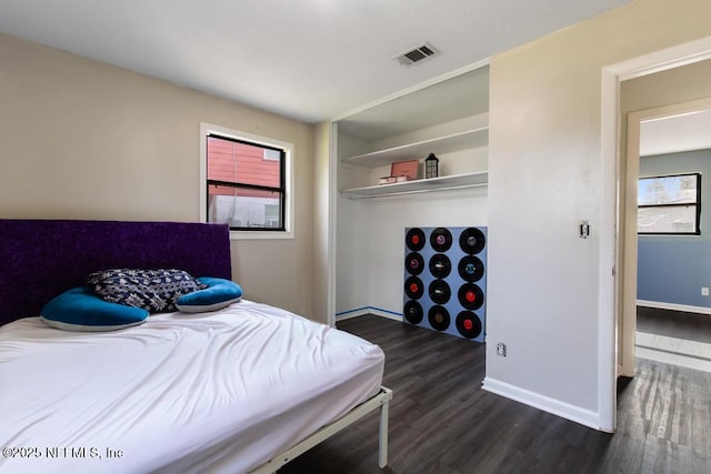 bedroom featuring a closet, dark wood finished floors, visible vents, and baseboards