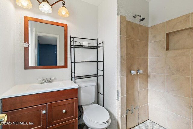 full bathroom featuring tiled shower, vanity, and toilet