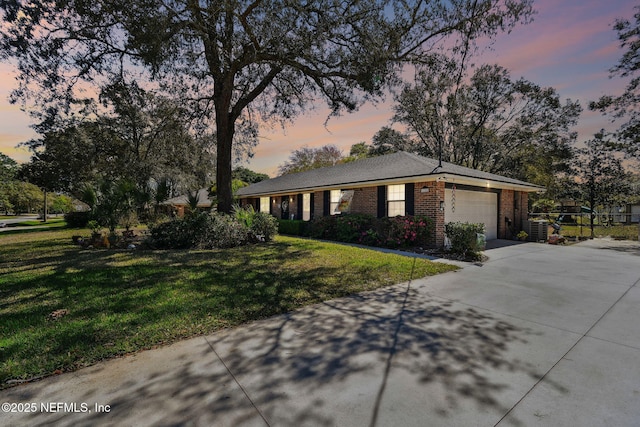 view of front of property with brick siding, a garage, driveway, and a front lawn