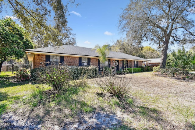 view of front of property with brick siding, a front lawn, and fence