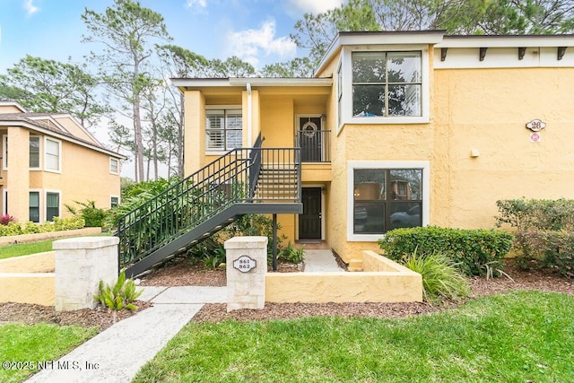 view of front facade featuring stairs and stucco siding