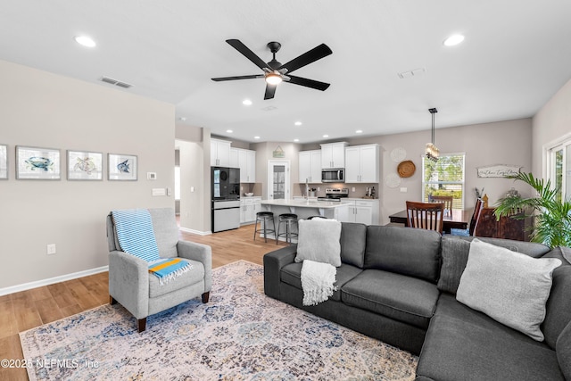 living area featuring ceiling fan, visible vents, and light wood-style floors