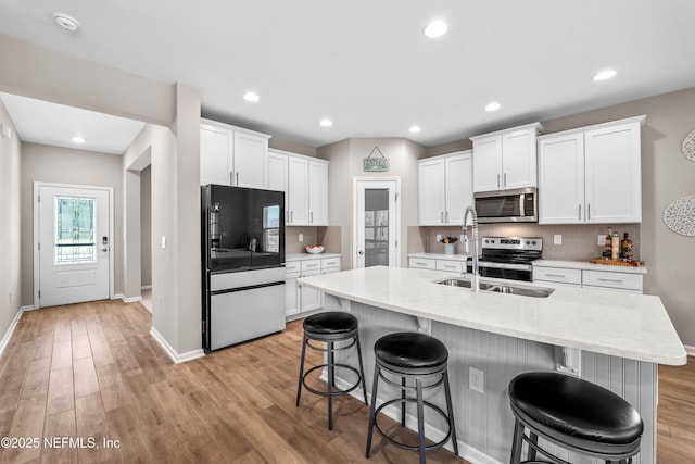 kitchen featuring appliances with stainless steel finishes, light wood-type flooring, backsplash, and a kitchen bar