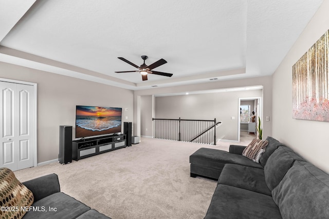 living area featuring carpet, a raised ceiling, visible vents, and baseboards