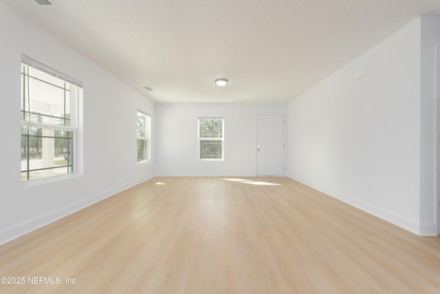 unfurnished room featuring light wood finished floors, baseboards, and a textured ceiling