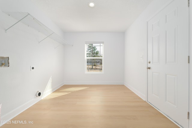 clothes washing area with light wood-style flooring, hookup for an electric dryer, laundry area, washer hookup, and baseboards