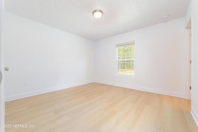 unfurnished room featuring light wood-style floors, a textured ceiling, and baseboards