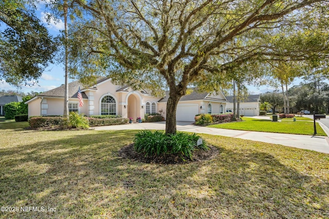 view of front of house featuring stucco siding, a front lawn, a garage, and driveway