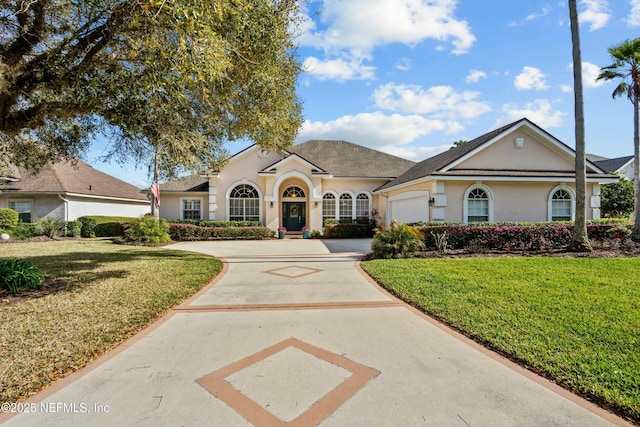 view of front of home featuring stucco siding, an attached garage, concrete driveway, and a front lawn