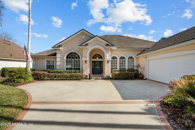 view of front facade featuring stucco siding, concrete driveway, an attached garage, and a shingled roof