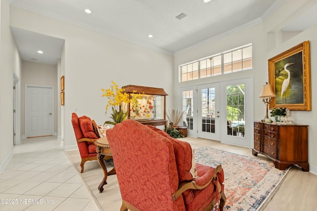 interior space with french doors, light tile patterned flooring, crown molding, baseboards, and a towering ceiling