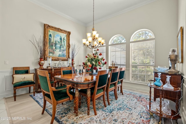 dining space with wood finished floors, a wainscoted wall, crown molding, a decorative wall, and a notable chandelier