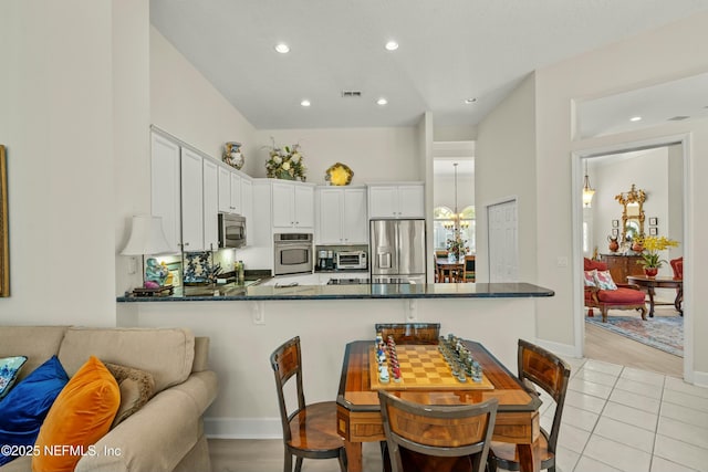 kitchen featuring visible vents, a toaster, appliances with stainless steel finishes, a peninsula, and white cabinetry