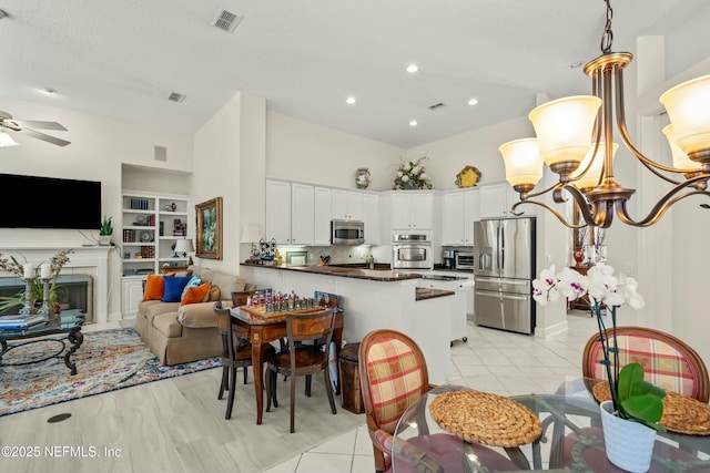 kitchen featuring built in shelves, visible vents, a peninsula, stainless steel appliances, and white cabinetry