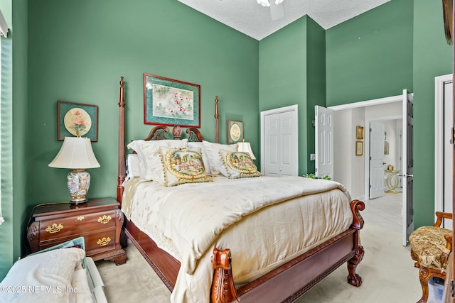 bedroom featuring a closet, a high ceiling, a ceiling fan, and a textured ceiling