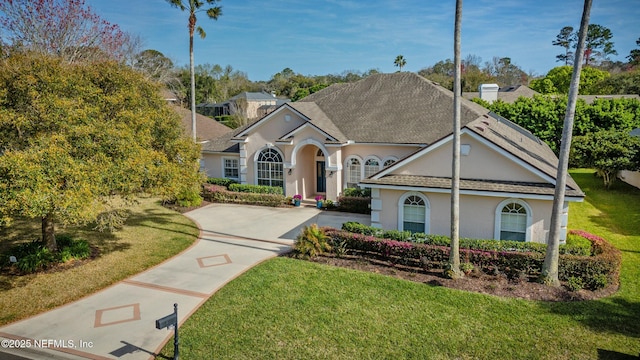 view of front of property with a shingled roof, a front lawn, and stucco siding