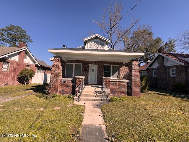 bungalow-style house with a porch, a front yard, and brick siding