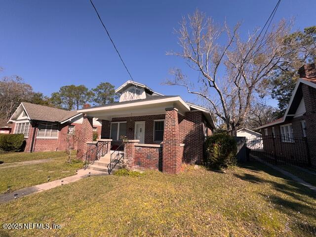 bungalow-style home featuring covered porch, brick siding, and a front lawn